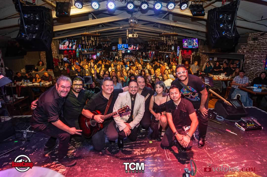 The band posing on stage in front of a packed, cheering crowd